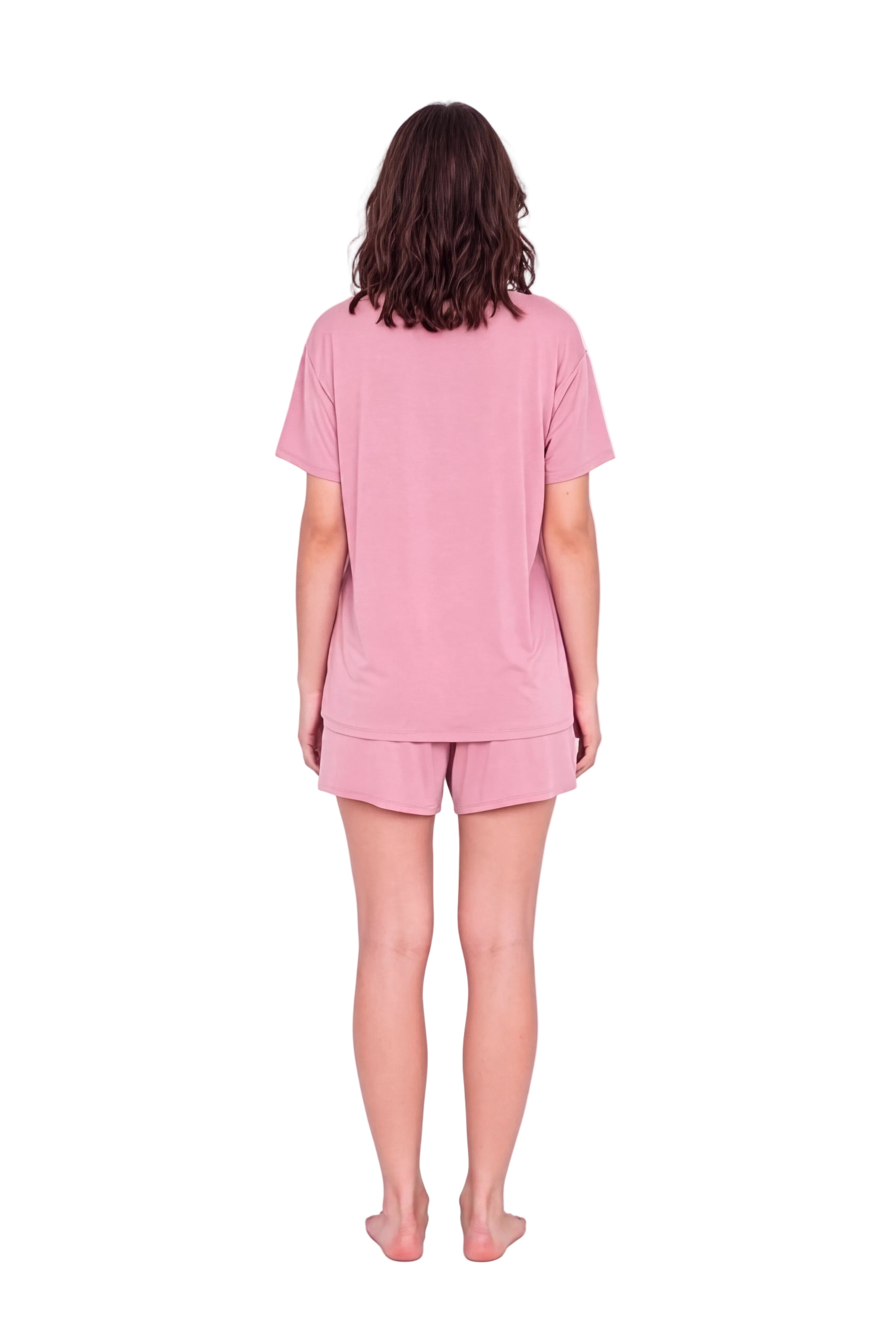 A woman viewed from behind wearing a light pink short-sleeve t-shirt and matching pink shorts against a plain white studio background.