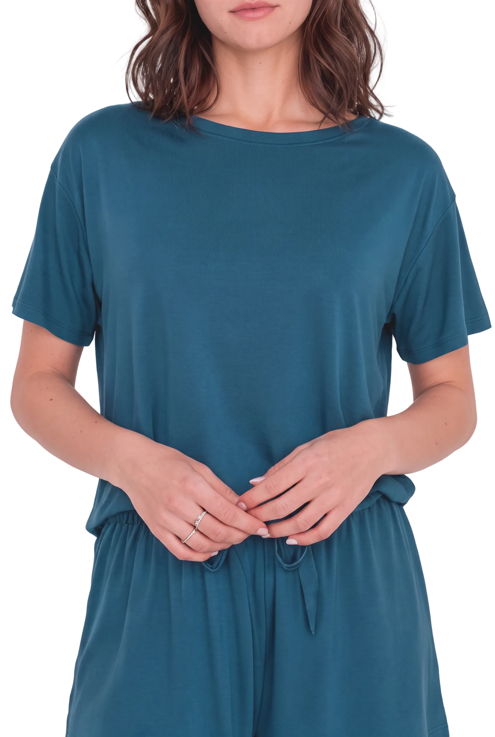 A woman wearing a teal blue short-sleeve tunic top and matching drawstring pants against a light beige background.