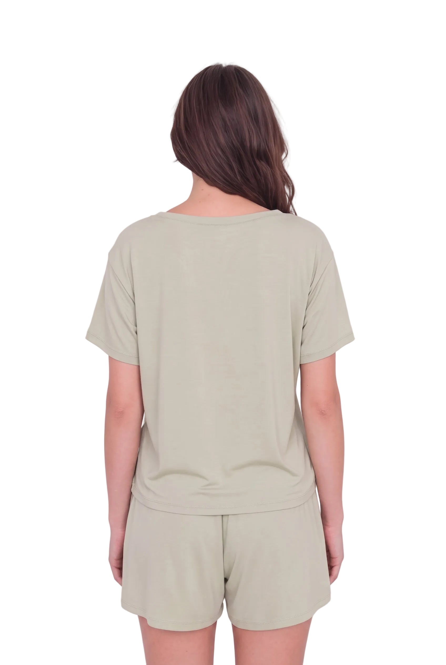 A woman viewed from behind wearing a light sage green short-sleeve t-shirt and matching shorts against a pale pink studio background.