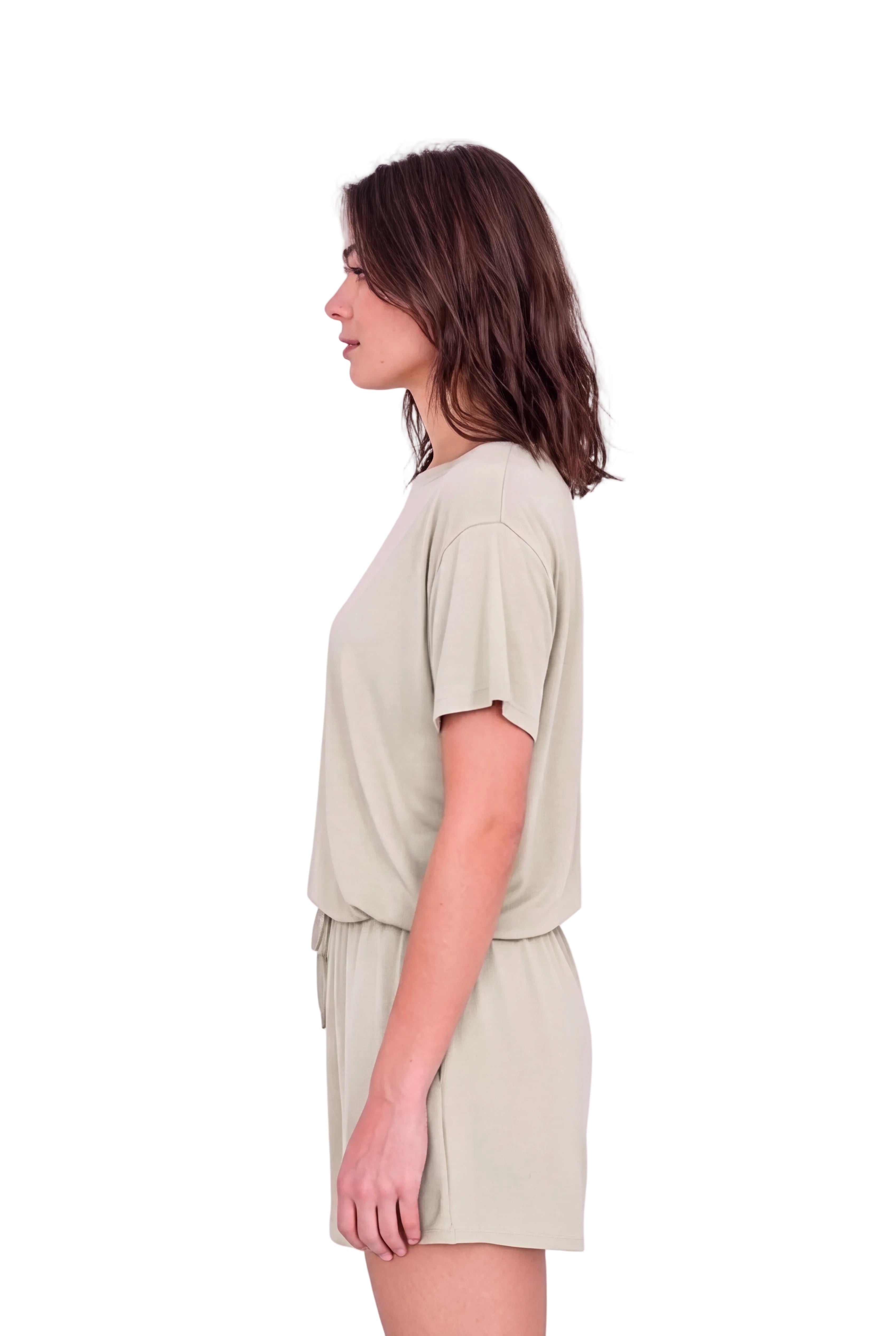 A woman shown in side profile wearing a light sage green short-sleeve top and matching shorts set against a plain white studio background.