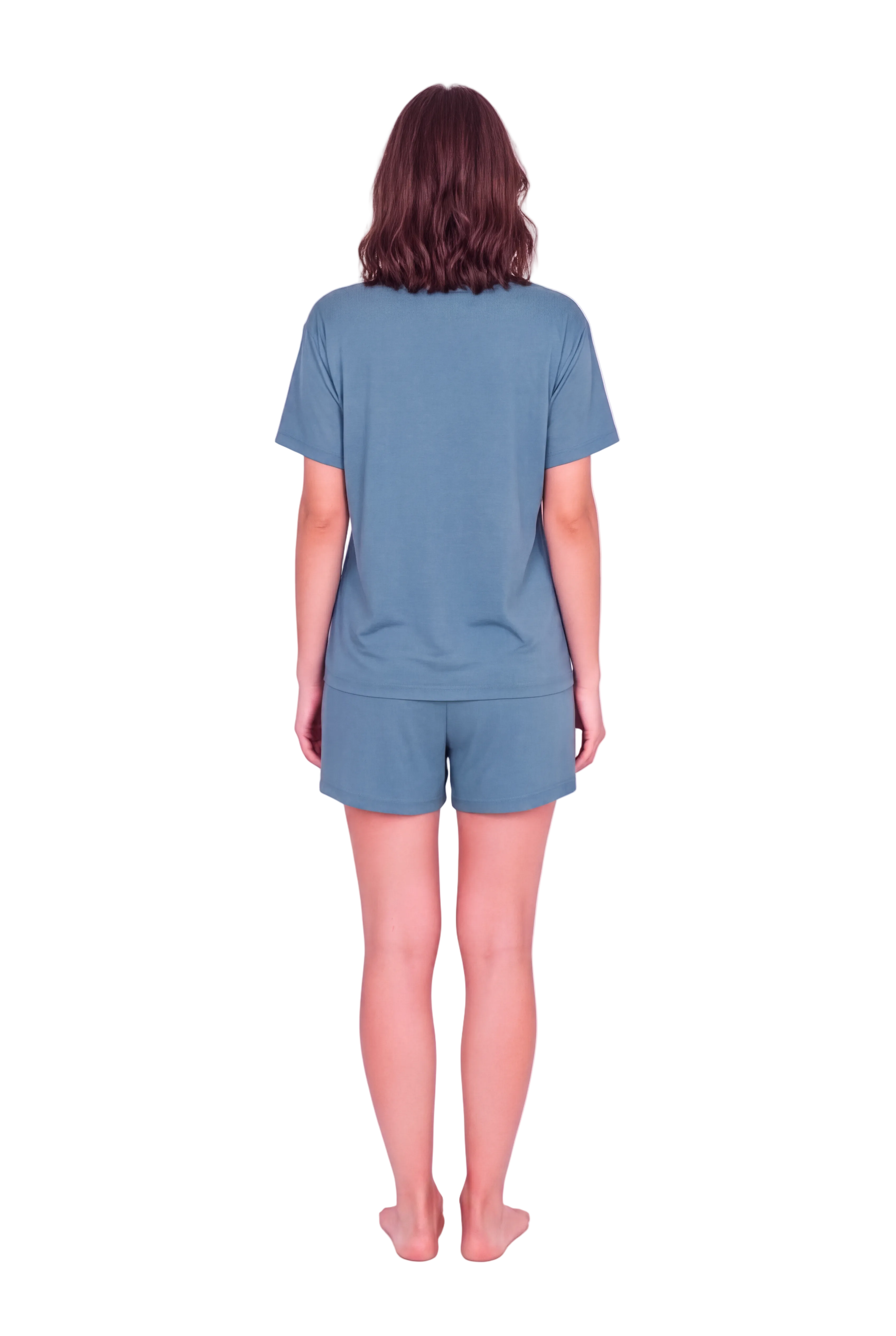 A woman viewed from behind wearing a matching dusty blue short-sleeve t-shirt and shorts set, standing against a solid pale pink studio background.