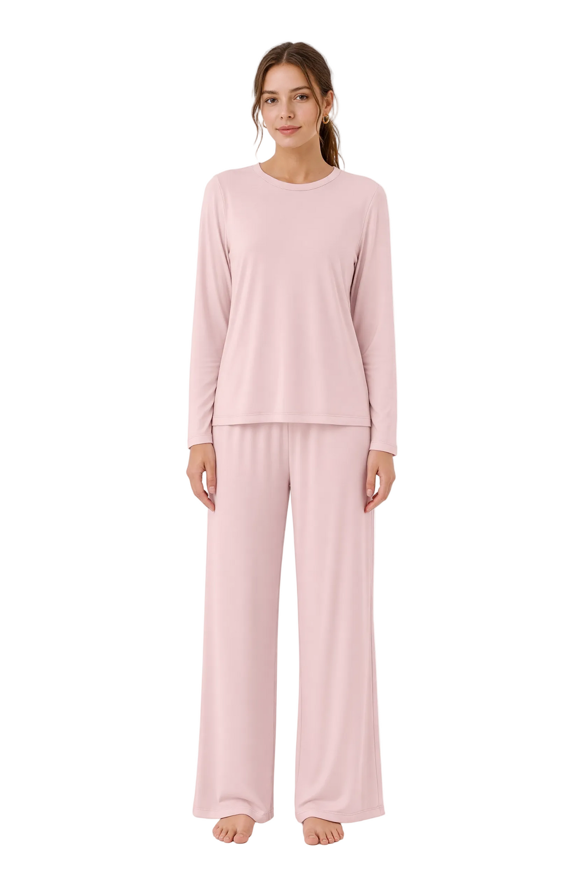 A woman modeling a light pink two-piece pajama set consisting of a long-sleeve crewneck top and matching wide-leg pants, photographed against a seamless white studio background.